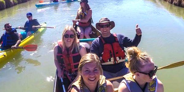 A happy group of people enjoying a canoe trip on a green river